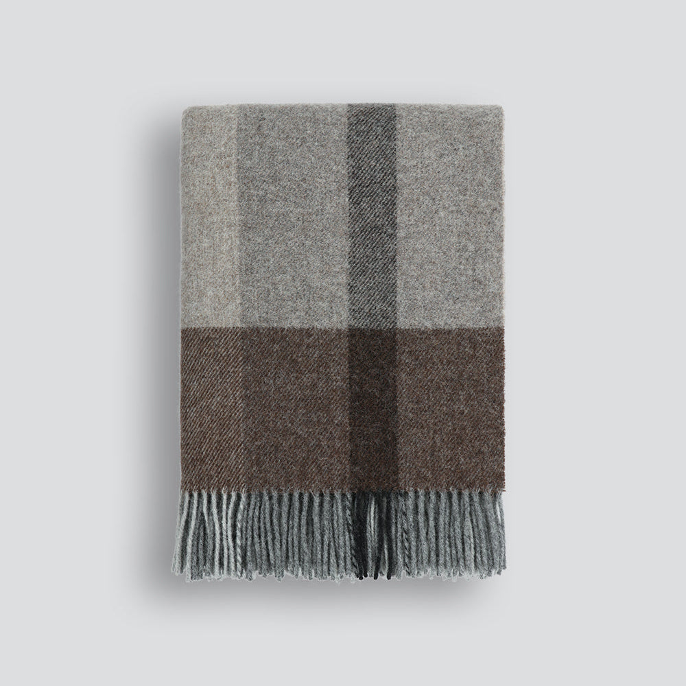 Plaid blanket with gray and brown check pattern on a light gray background