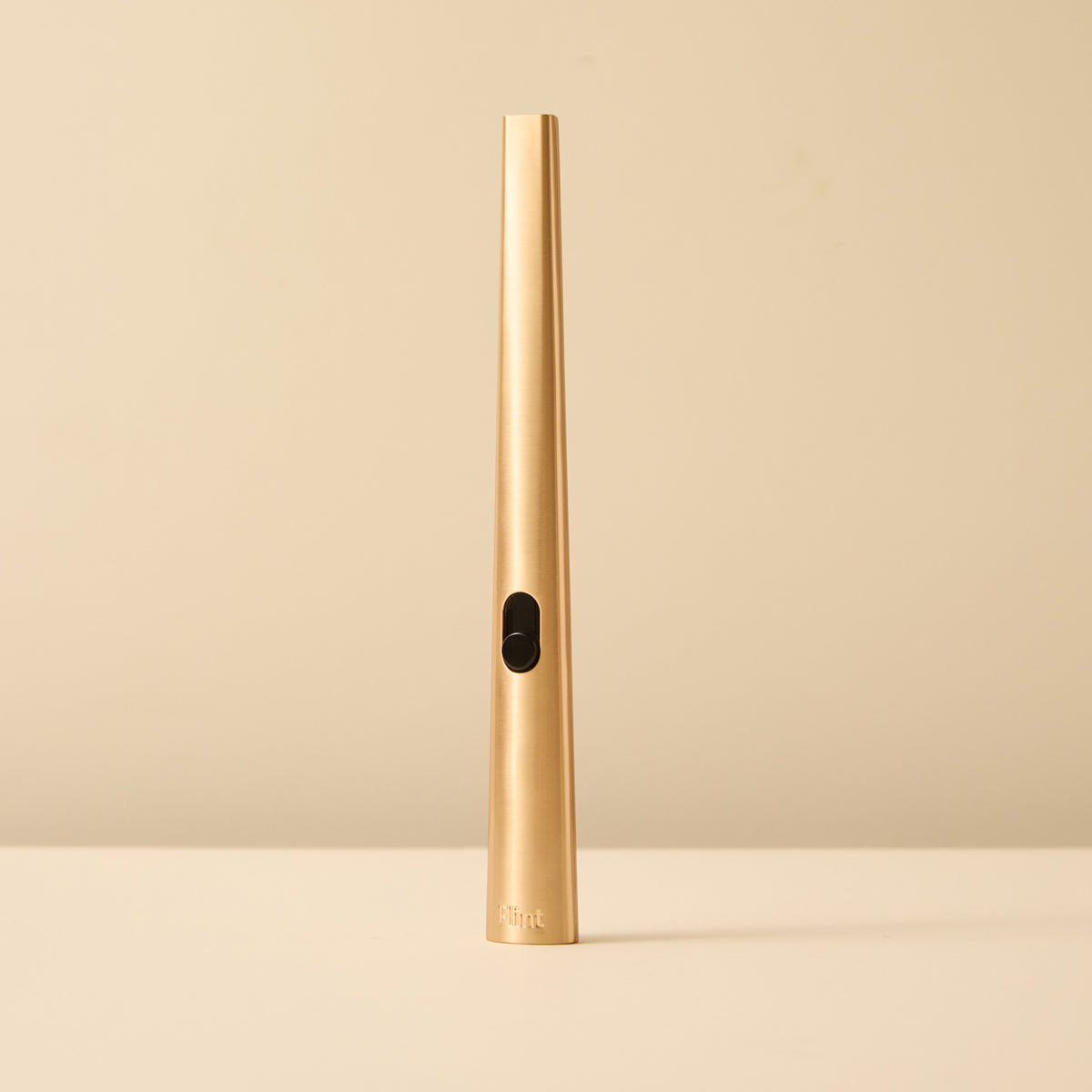 A slim gold refillable lighter standing upright