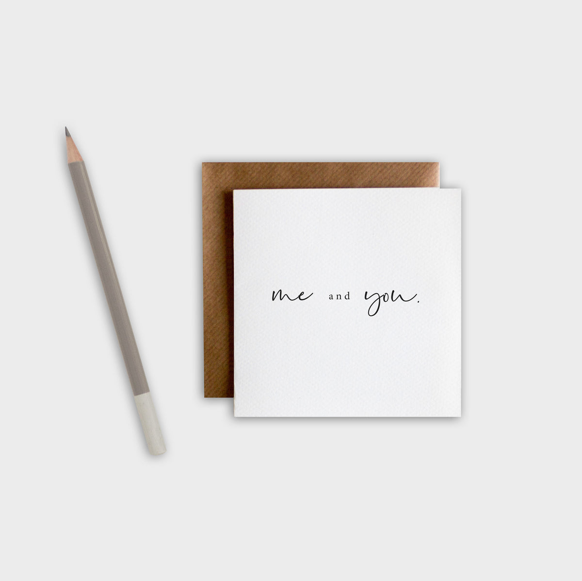 Greeting card with 'me and you' text, brown envelope, and pencil on a white background