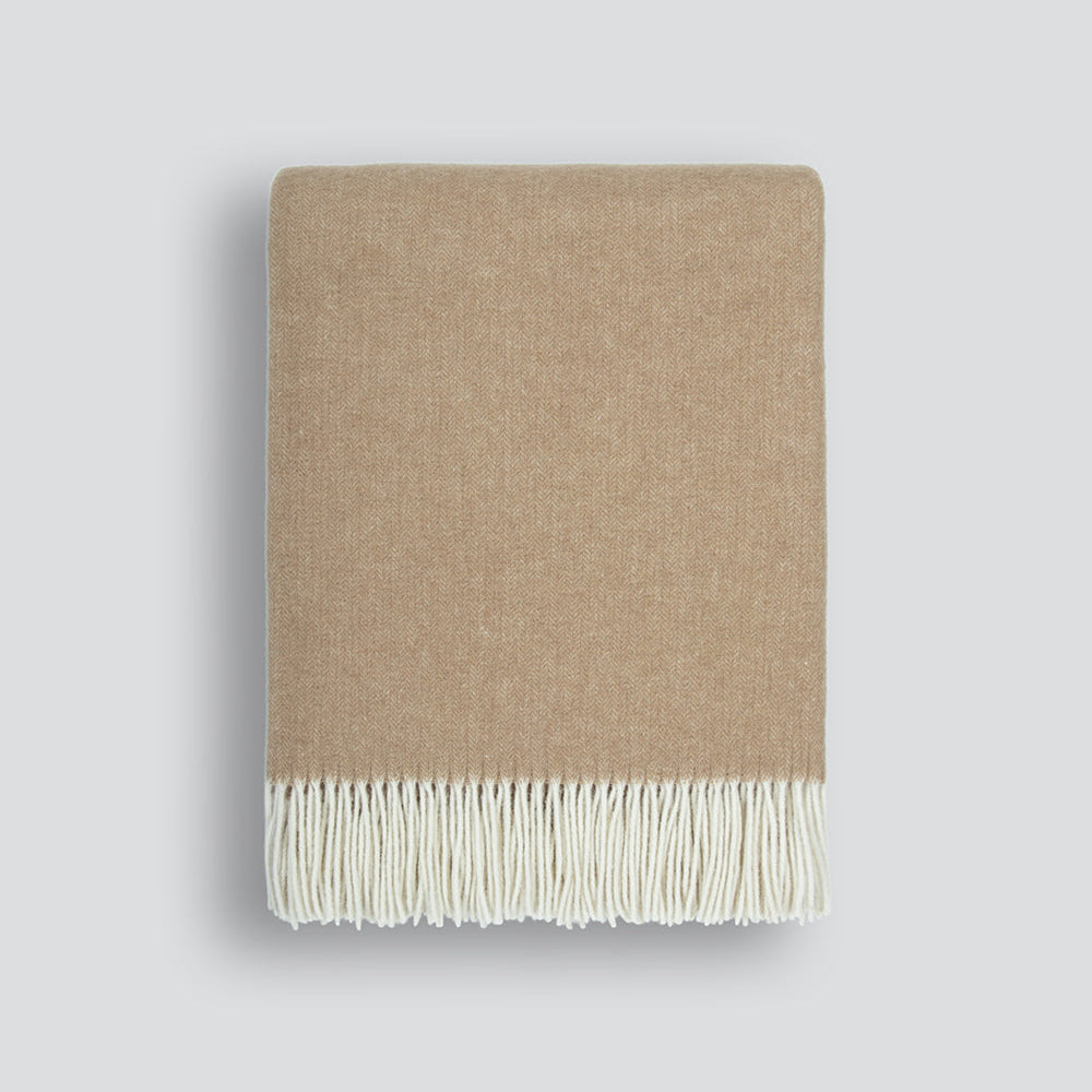 Beige blanket with white fringe on a light gray background