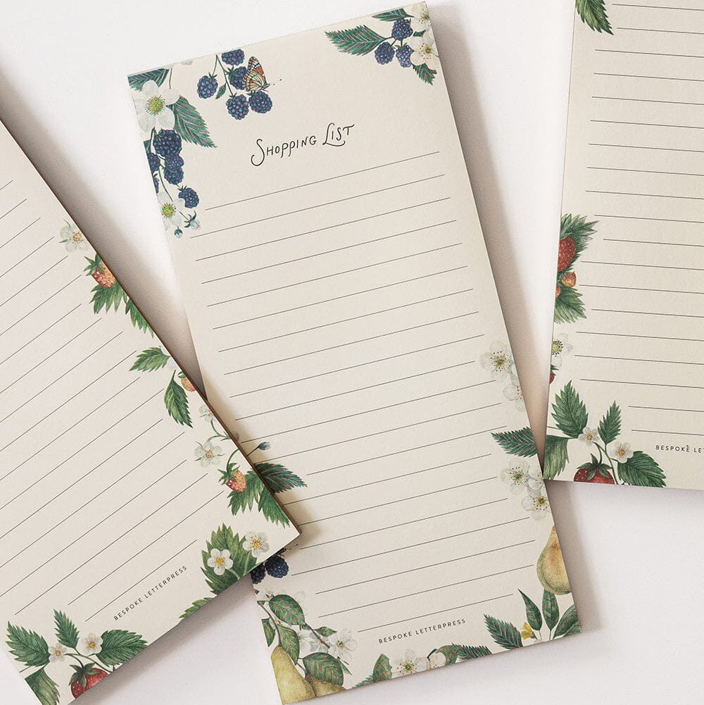 Set of three notepads with floral and fruit design on a white background