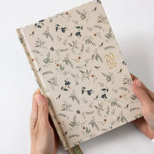 Floral-patterned notebook held by hands on a white background