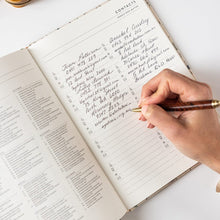 Hand writing in a notebook with a pen on a white surface