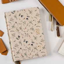 Floral-patterned notebook with a pen holder and pens on a light background