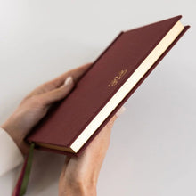 Person holding a linen covered planner with gold foil edging.