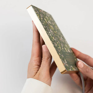 Hand holding a floral notebook with gold foil edges