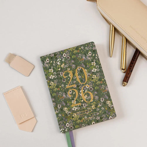 Floral notebook with '2026' on a white surface with stationery items.