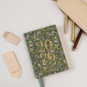 Floral notebook with '2026' on a white surface with stationery items.