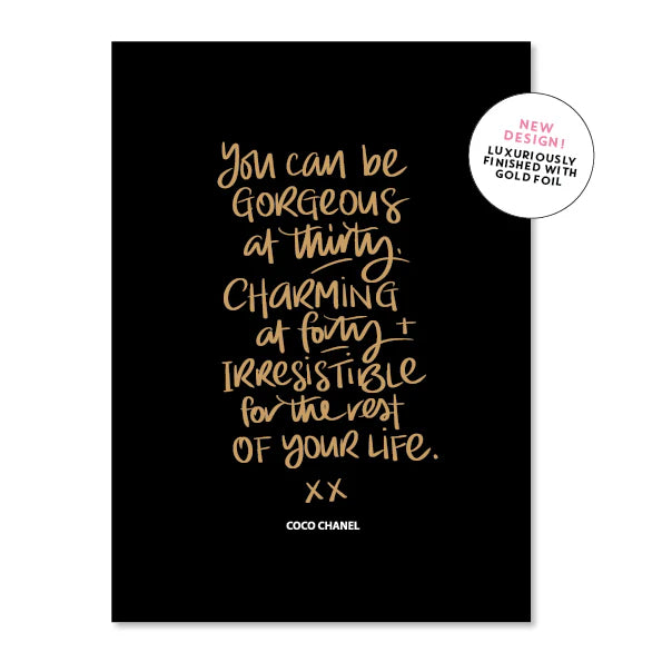 A black greeting card printed in gold script with a Coco Chanel quote