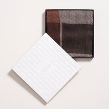 Brown and gray checkered scarf with a white box on a light beige background