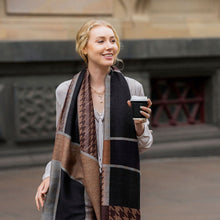 Woman wearing a patterned scarf and holding a coffee cup outdoors.
