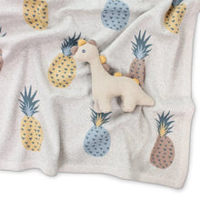 Knitted dinosaur baby rattle toy in linen colour on baby blanket with pineapple design