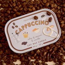 A Paddywax Cappuccino soy wax candle tin surrounded by scattered coffee beans on a warm cream background. 