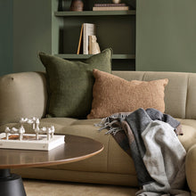 Cozy living room with a beige sofa, green and brown cushions, and a wooden coffee table.