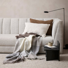 Gray sofa with a blanket and pillows in a living room setting.