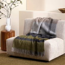 Gray and green plaid blanket draped over a gray sofa in a living room setting.