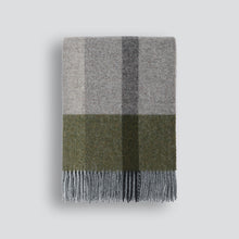 Plaid blanket with gray and green check pattern on a light gray background