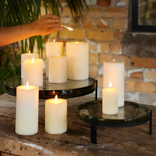 Candles being lit on a rustic wooden surface with a brick wall background