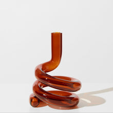 Spiral-shaped amber glass vase on a white background
