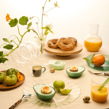 Table setting with fruit, pastries, and drinks on a light background