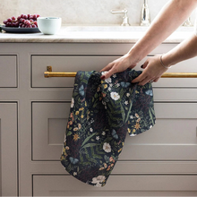 Person hanging a floral towel on a kitchen cabinet handle.