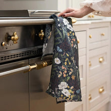 Person using a floral towel to open an oven door in a kitchen.