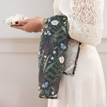 Person wearing a white lace top and holding a plate of food with floral tea towel