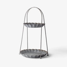 Two-tiered metal stand with scalloped edges on a white background