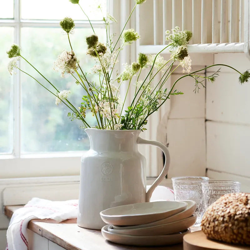 White jug with flowers on kitchen bench top