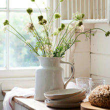 White jug with flowers on kitchen bench top