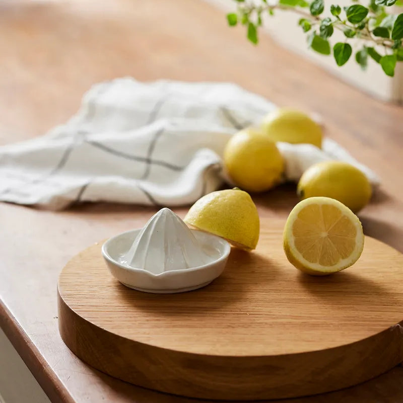 White manual juicer on a wooden cutting board with lemons