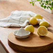 White manual juicer on a wooden cutting board with lemons