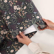 Person holding a roll of floral-patterned paper with hands visible