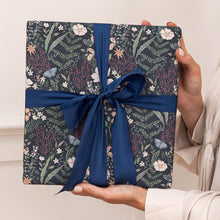 Gift box with floral pattern and blue ribbon held by a person