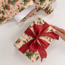 Gift box wrapped in strawberry patterned paper with a red ribbon, on a white surface.