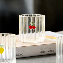 Clear glass candle holder with cherry design on a book