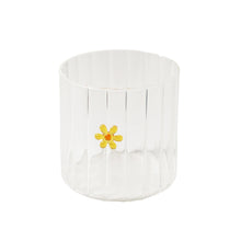 Clear glass with a yellow flower on a white background