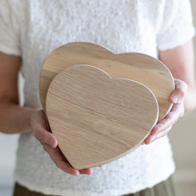 Person holding two heart-shaped wooden boards

