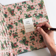 Floral-patterned notebook with a hand holding a pen on a white background