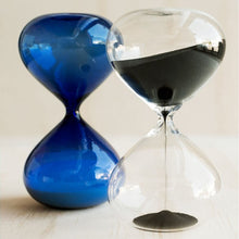 Two hourglasses, one blue and one clear with black sand, on a light background.