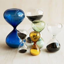 Colorful hourglass-shaped sand timers on a light wooden surface.
