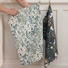 Floral-patterned fabric hanging on a rack against a neutral background