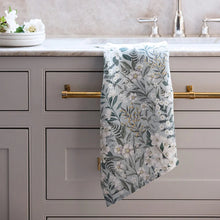 Floral-patterned towel hanging on a kitchen cabinet handle with a neutral color scheme.