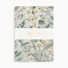 Floral patterned tea towel packaging on a light gray background