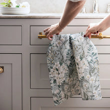 Person holding a floral towel over kitchen cabinets