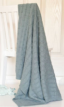 Sage Knitted baby blanket hanging on white chair