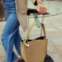 Person holding a beige handbag with a blurred background