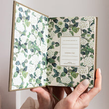 Hand holding a floral-patterned notebook with a white background