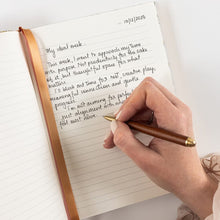 Hand writing in a journal with a pen on a white background