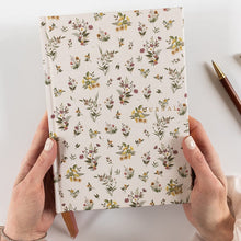Floral-patterned notebook held by hands on a light background